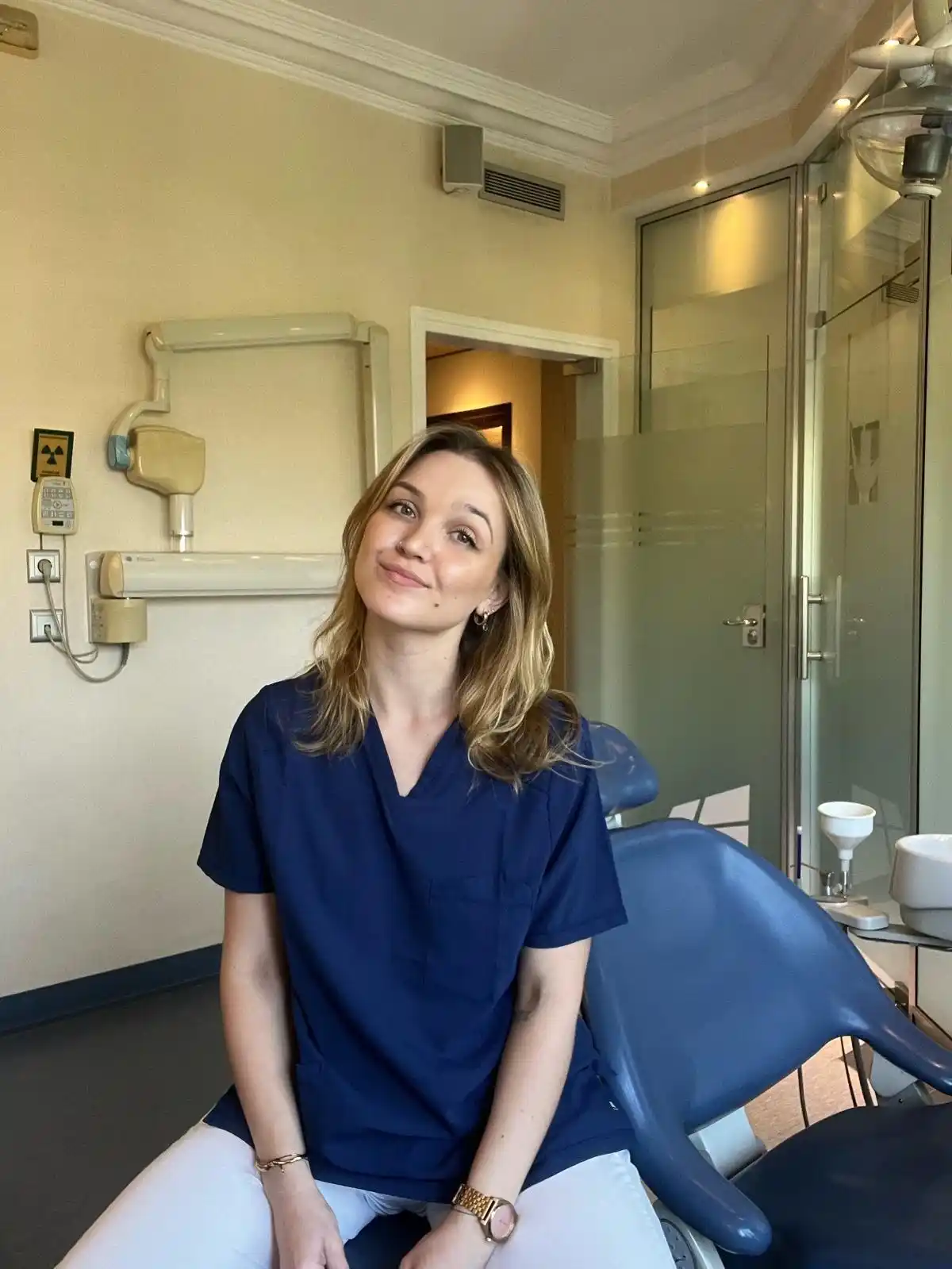 Dana Milina, especialista en fisioterapia maxilofacial, sonriendo a mirando a cámara en consulta con la cabeza ladeada, pelo suelto 
